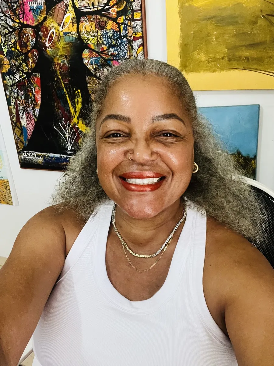 Tami Dee García smiling in front of colorful artwork